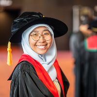 Woman smiling at the camera, wearing a bonnet at a college ceremony in Wellington.