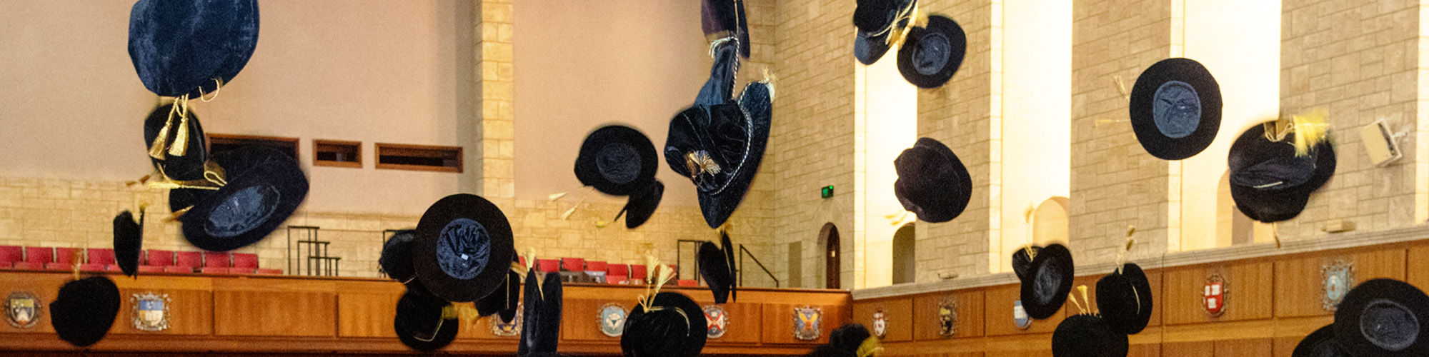 New Fellows at a college ceremony throwing their caps in the air.