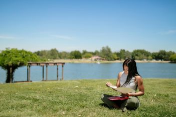 image of woman sitting crossed legged in a park and reading notes