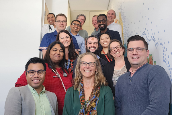 Group of more than 10 people smiling at the camera in a stairwell.