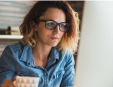 woman wearing glasses looking at her computer.